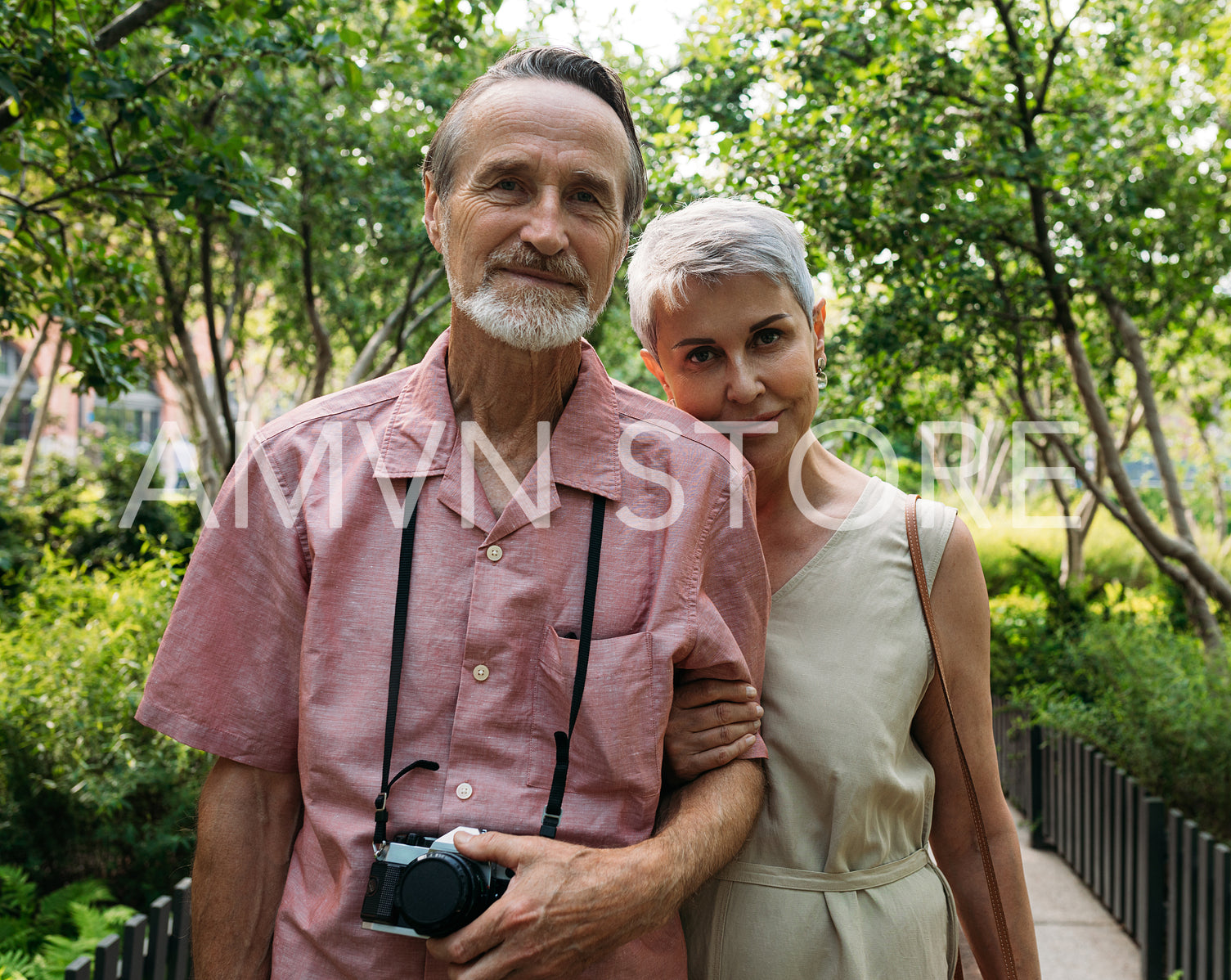 Portrait of two aged people looking at a camera in the park. Mature husband and his wife looking at the camera.