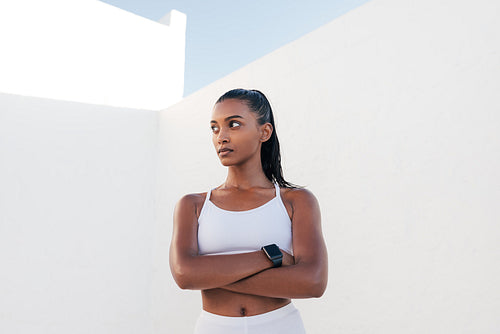 Strong and confident fitness influencer. Woman in white sports clothes with crossed hands.