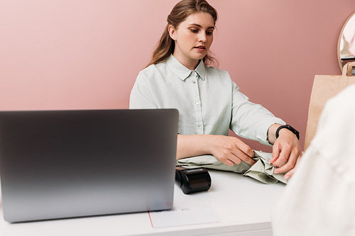 Small boutique owner folding clothes for customer at checkout co