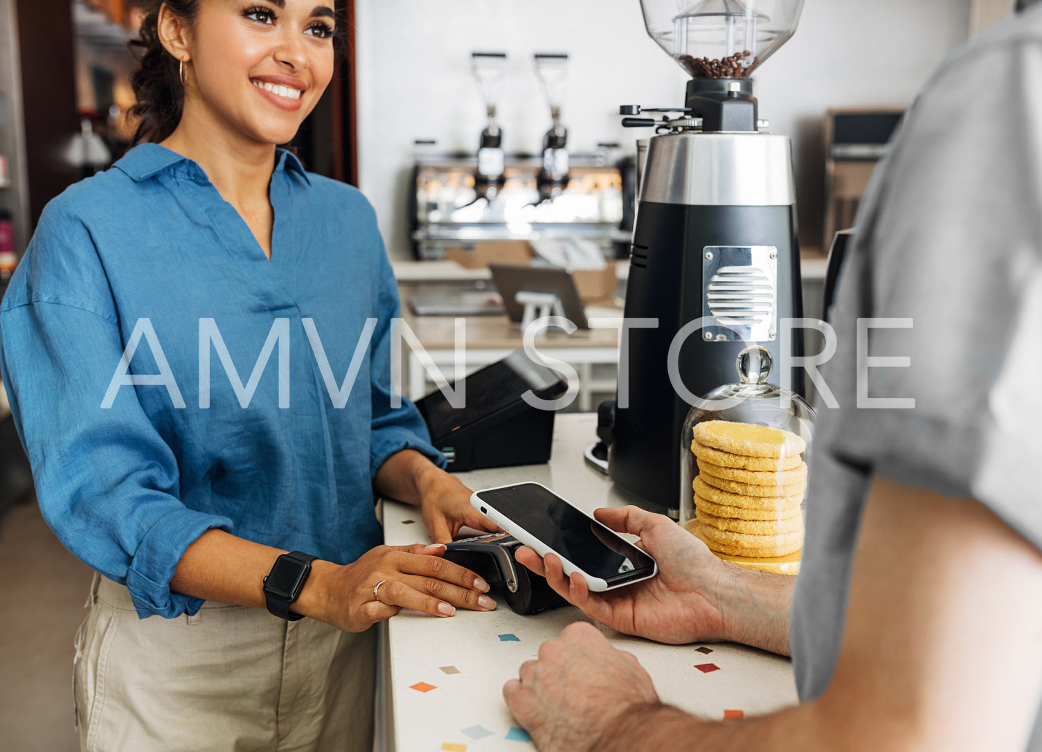 Hand of a customer at a cafe paying his bill using a mobile phone. Female entrepreneur holding a POS terminal while client paying using NFC technology.	