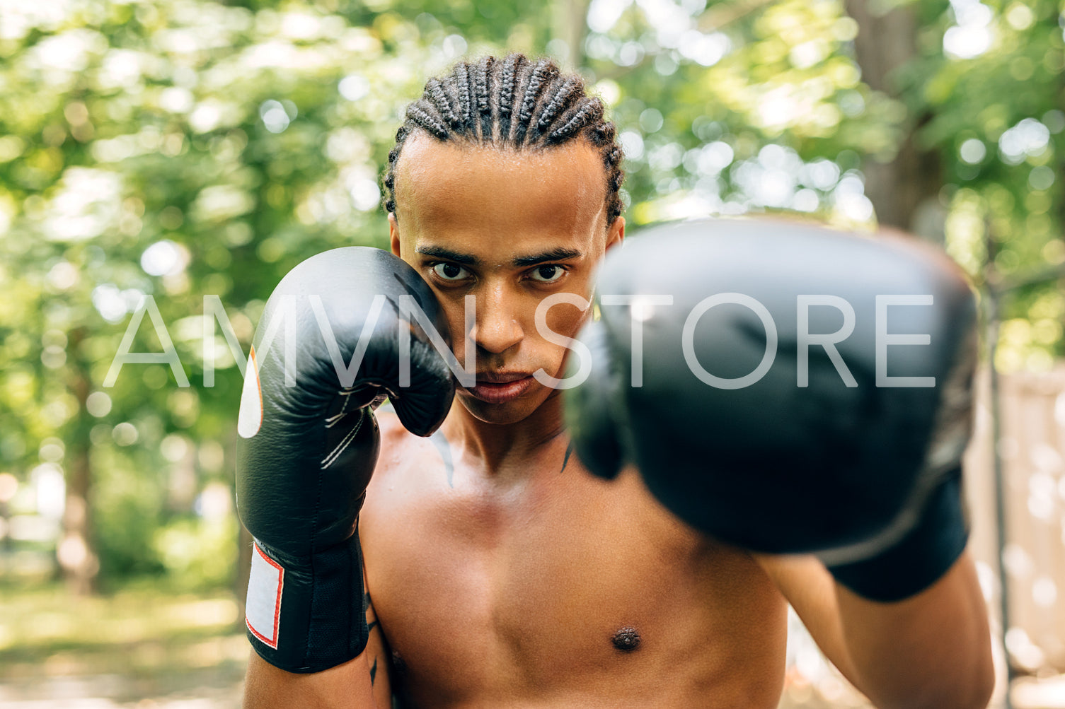 Athlete practicing punches outdoors on sports ground. Close up of a sweated male boxer doing shadow boxing.	