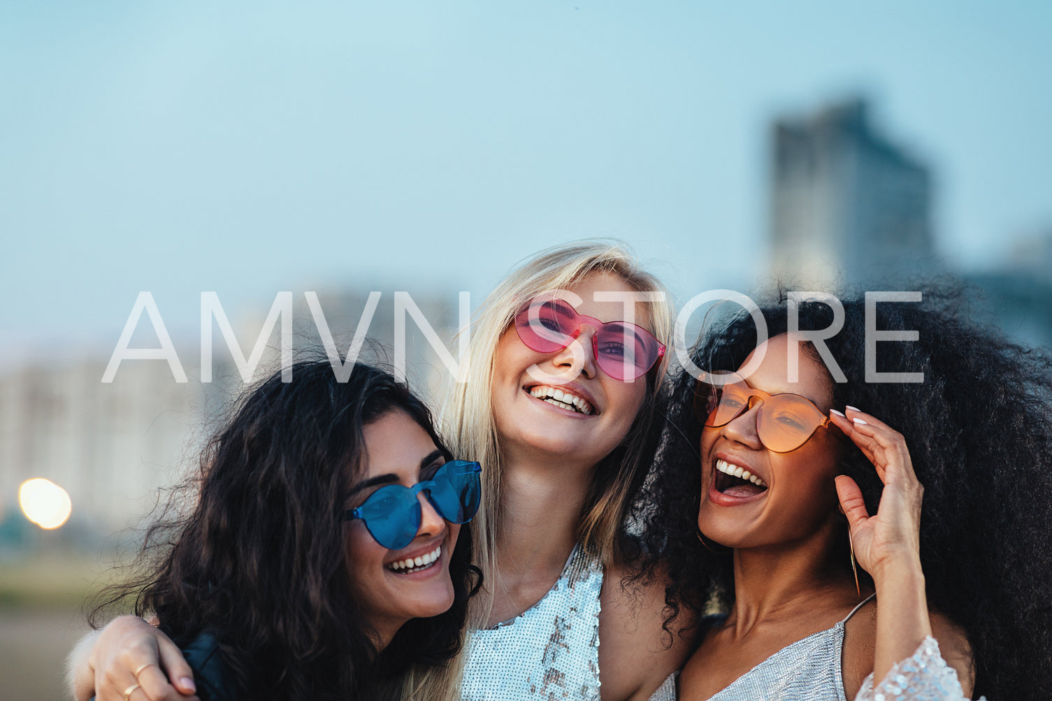 Three beautiful women with colorful sunglasses standing at evening outdoors	