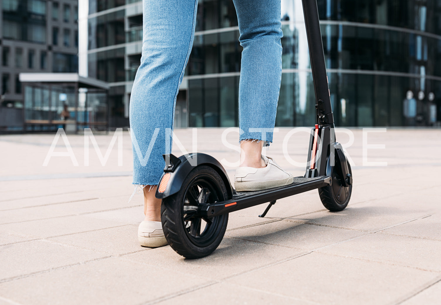 Unrecognizable woman standing on an electric scooter in the city