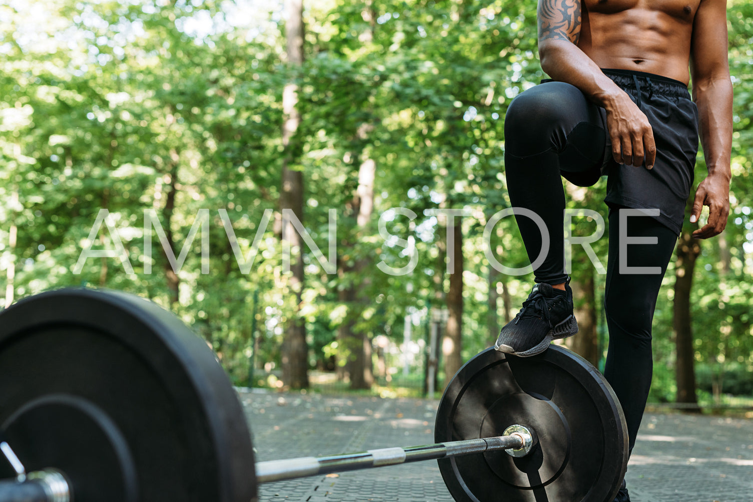 Cropped shot of a young muscular man standing outdoors after training. Unrecognizable athlete resting during exercises standing at the barbell.	