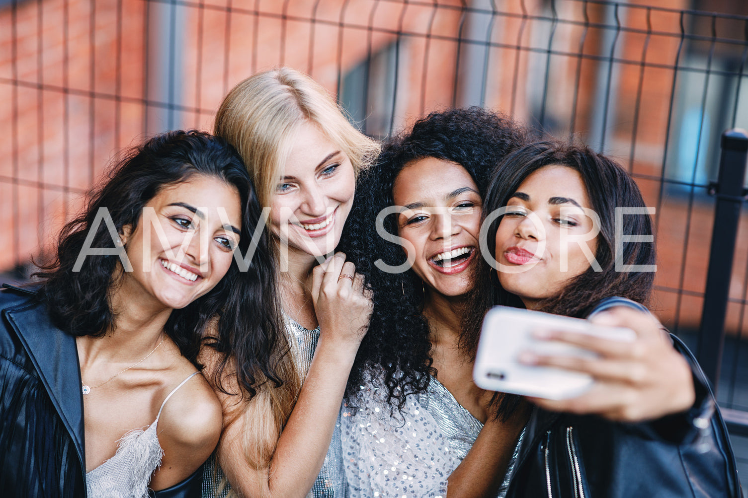 Group of happy female friends making photographs on smartphone outdoors	