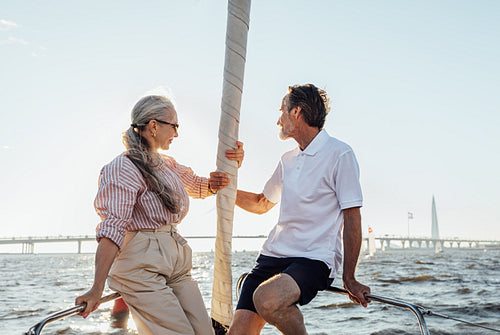 Elderly people sitting on sailboat bow and looking into distance