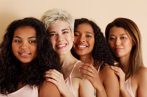 Four young females with different skin tones looking at the camera. Diverse women standing together.