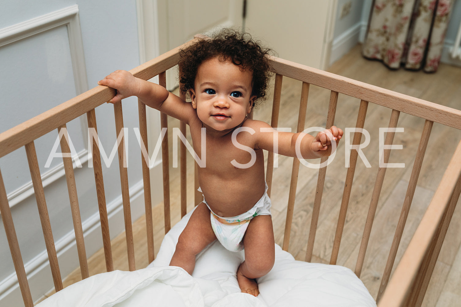 Toddler boy standing in a crib. Smiling child trying to walk.	