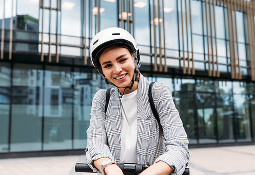 Portrait of a cheerful woman with safety helmet on her head standing against building