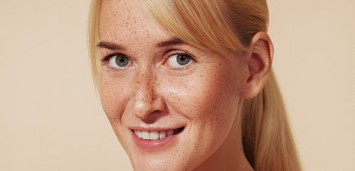 Close-up portrait of a smiling woman with blond hair and freckles. High-detailed portrait of a young cheerful female with naturally smooth skin.