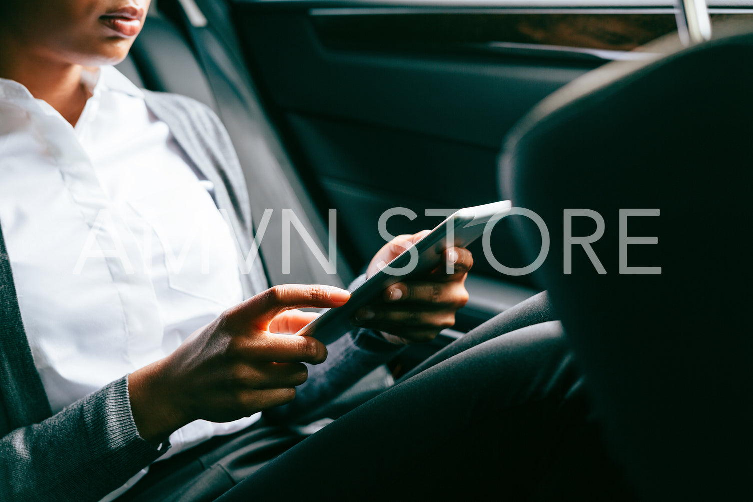 Unrecognizable woman using digital tablet, sitting on back seat of a car	