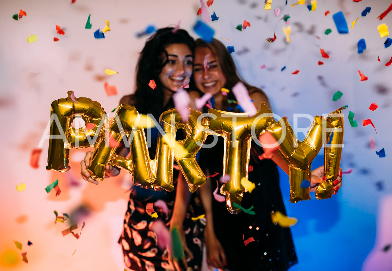 Two happy girls standing near a wall under confetti	