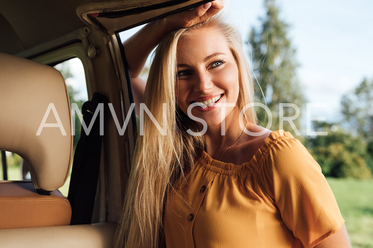 Beautiful blond woman in casual clothes leaning on camper van looking away