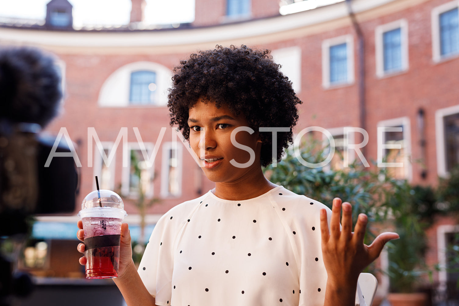 Young female influencer with curly hair filming on drsl camera outdoors