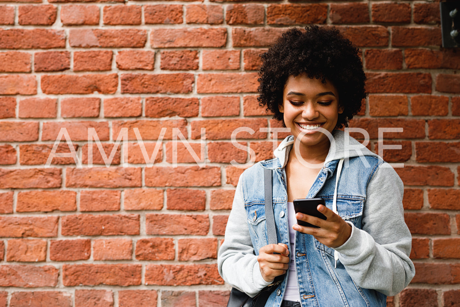 Happy hipster girl looking at her smartphone. Woman sends a message from cell phone.	