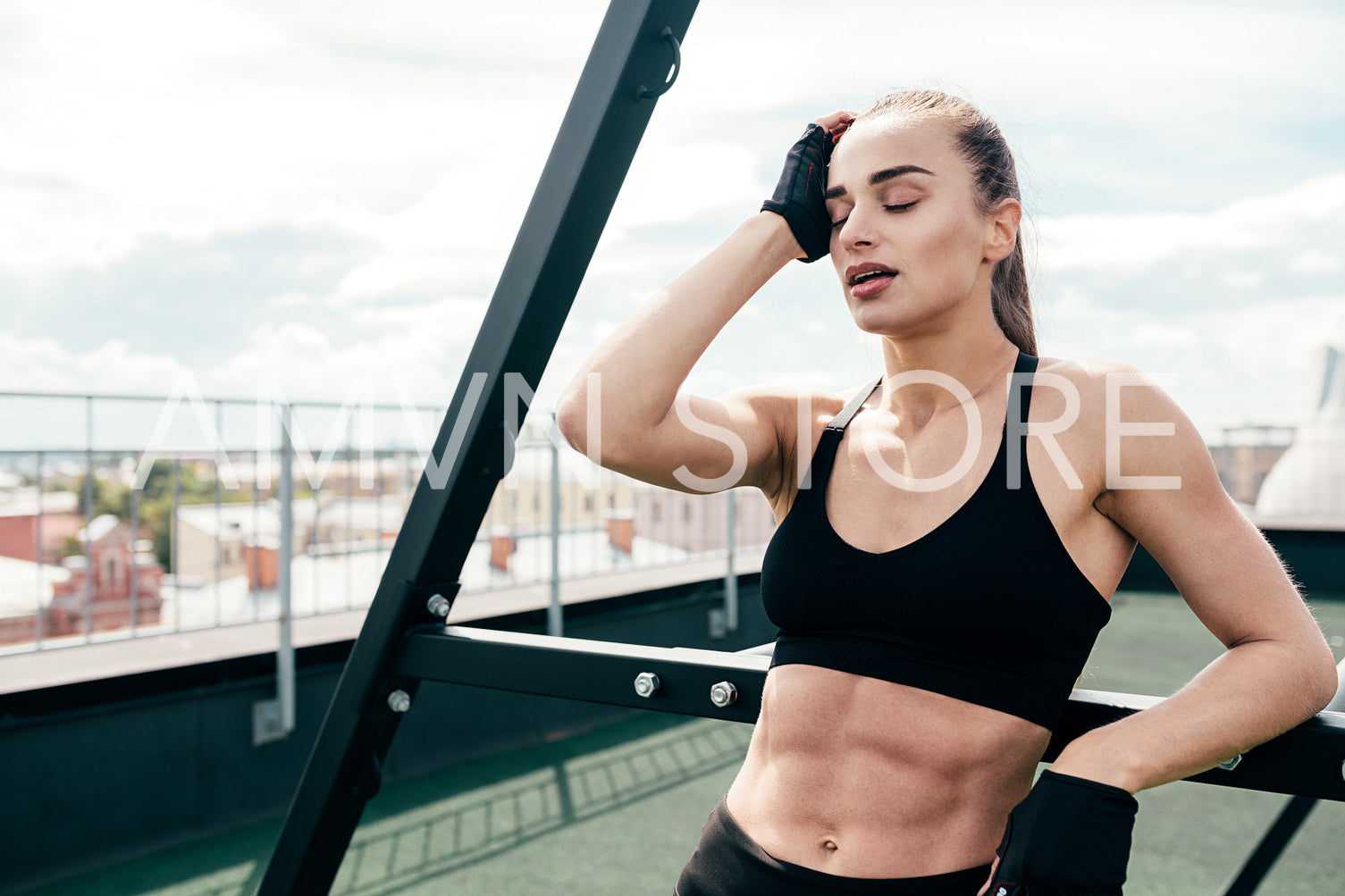 Tired woman having rest after workout on a terrace at power rack	
