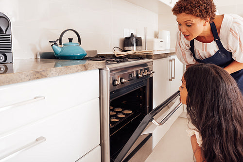 Girl and her granny opens the oven and looking inside