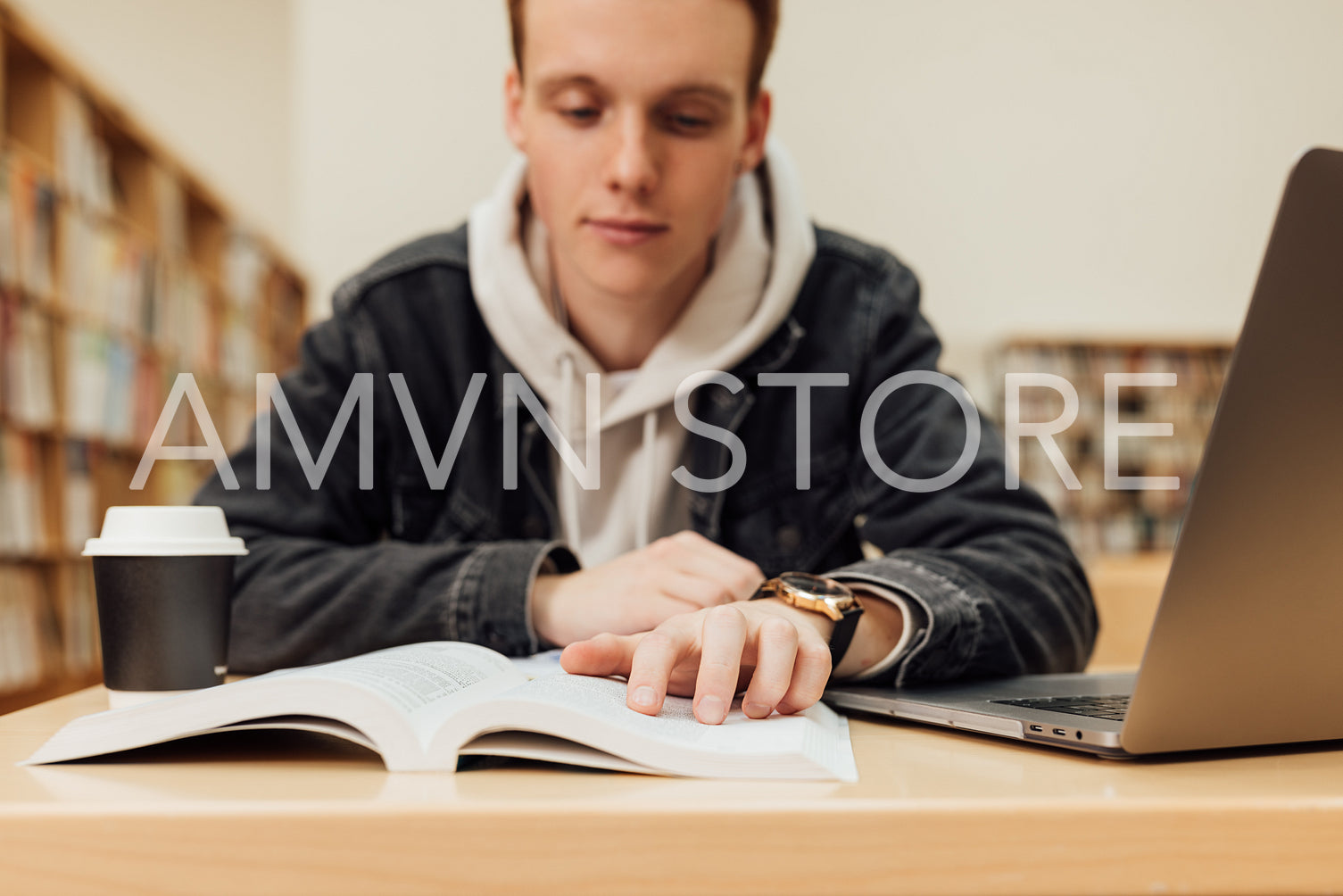 Close up of male hand on a book. University student reading from book while sitting in library.