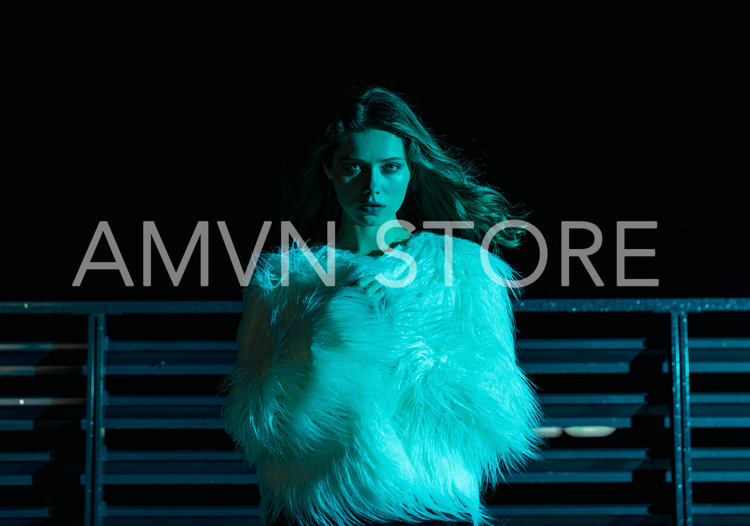 Woman in stylish fur coat standing at night under blue neon light	