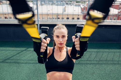 Young woman exercising with suspension ropes outdoors