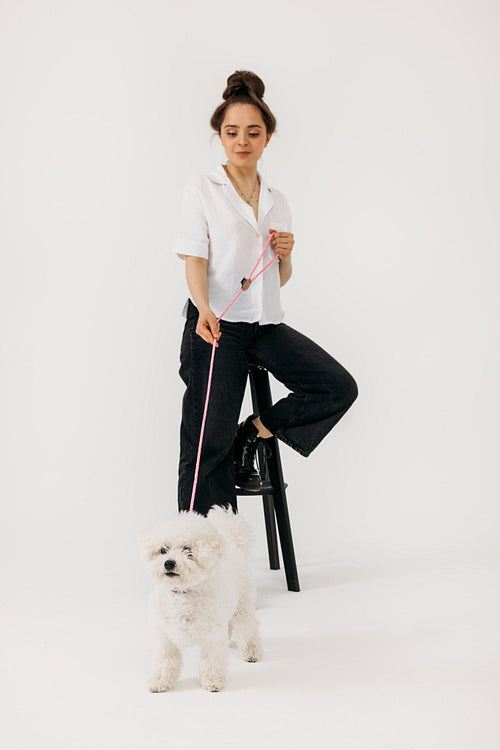 Woman sitting on a chair in studio with a dog on a lead