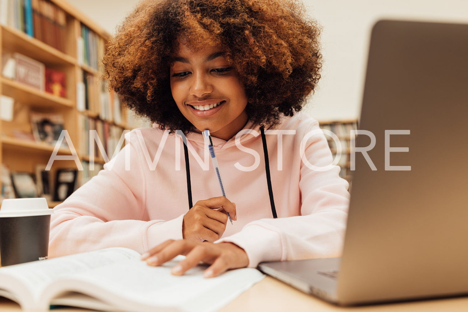 Young female in a school library working on laptop. Woman studying on school assignment.