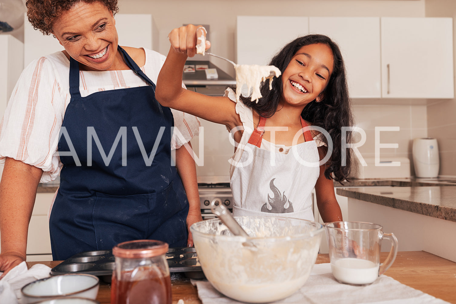 Happy girl scoops batter from a bowl with a spoon