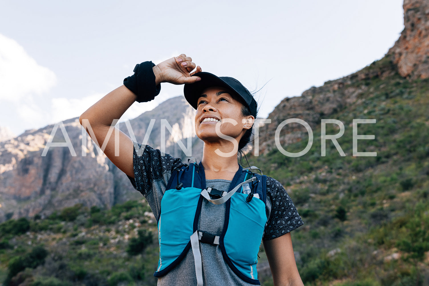 Smiling woman hiker looking up. Female in sports clothes holding cap and searching trail.