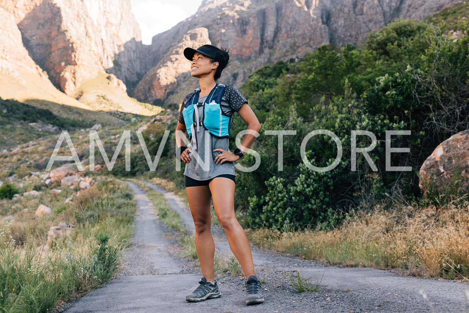 Woman runner looking away while standing on a abandoned road in valley