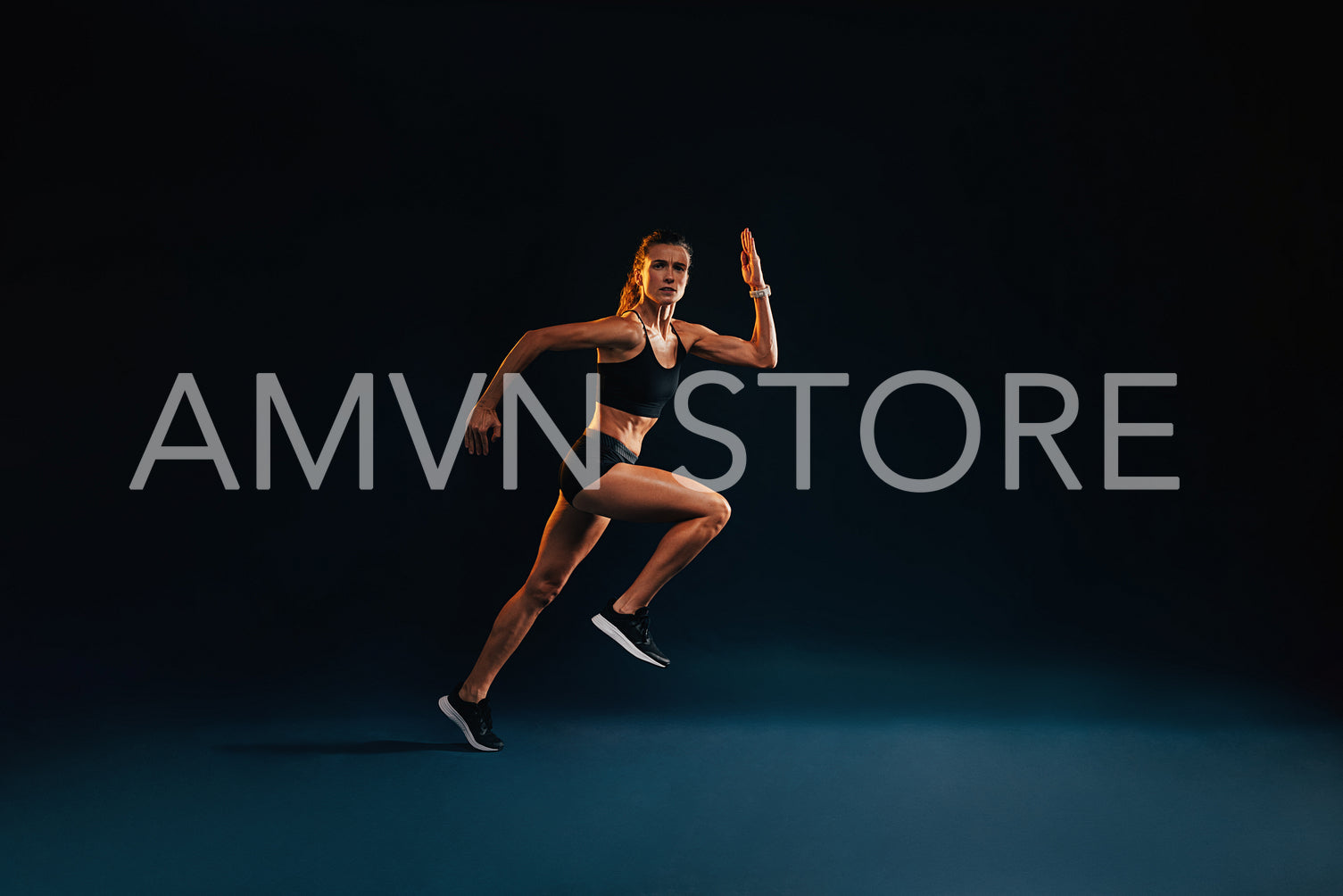 Young woman starting to run. Strong female athlete running on black background.