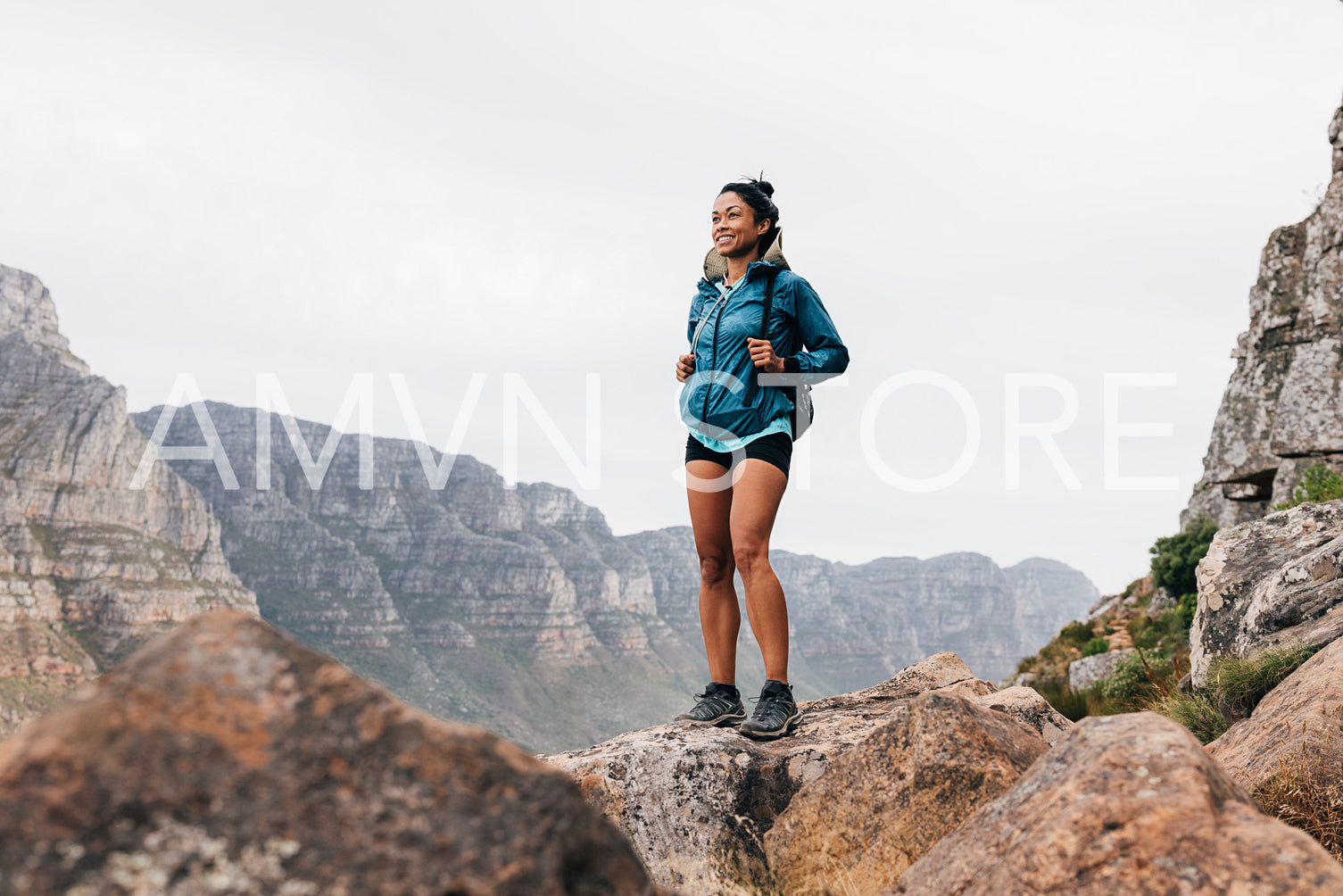 Smiling woman hiker enjoying the view. Young fit female in sports clothes enjoying the scenery during a mountain hike.