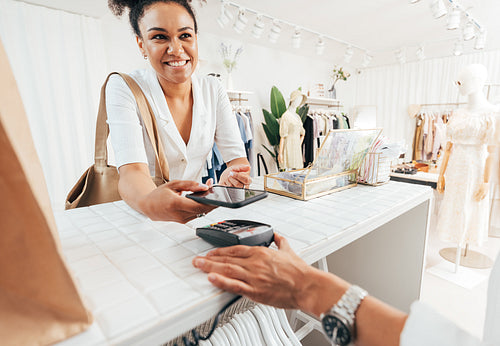 Happy customer paying through smartphone at a counter in a clothing store