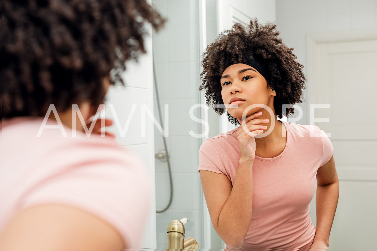 Beautiful young woman inspecting her skin in the bathroom mirror at home	