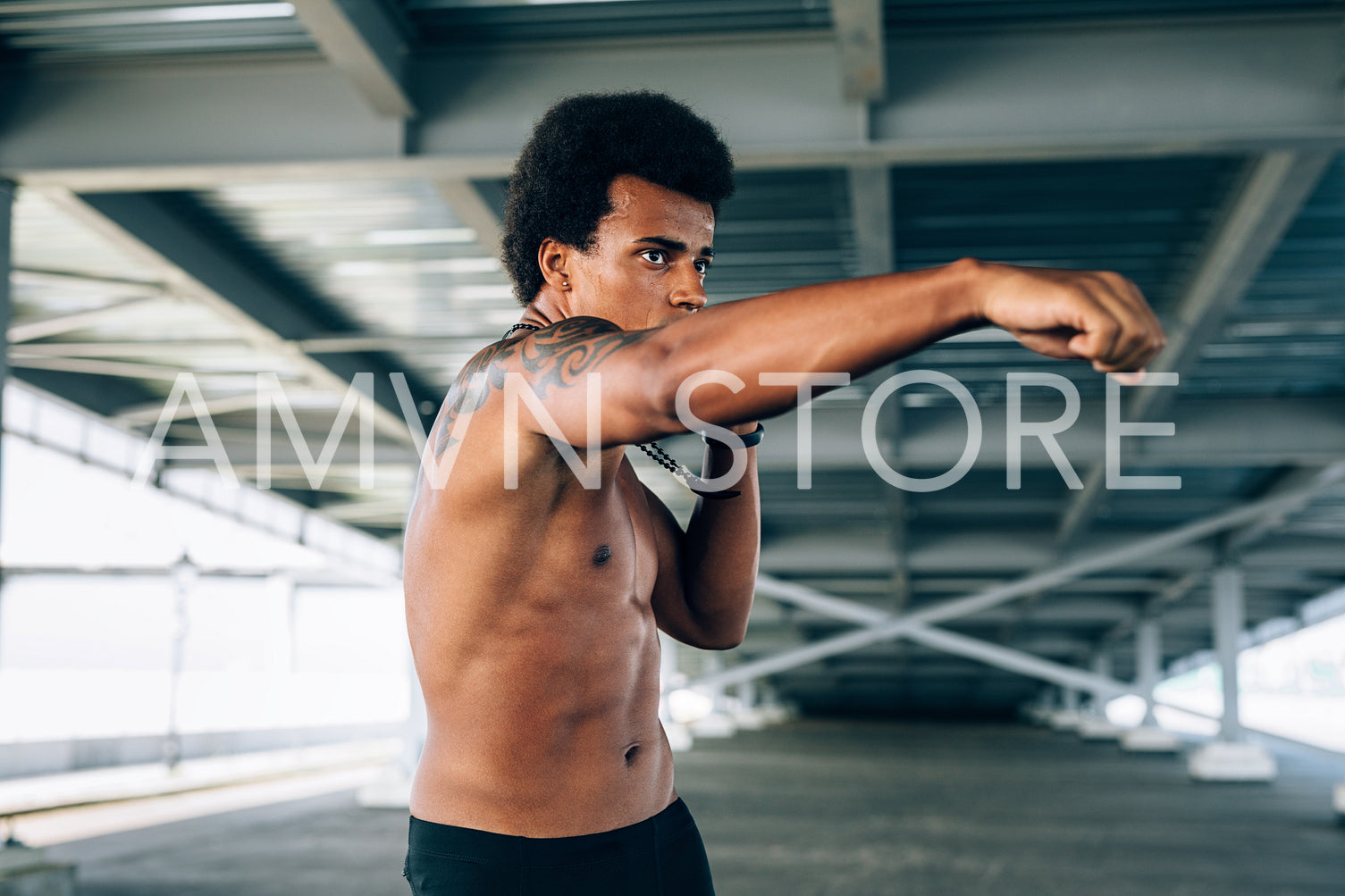 Male boxer practicing her punches under a bridge, doing shadow boxing	