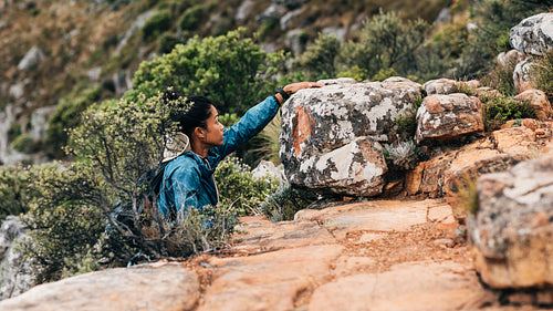 Side view of woman hiker climbing up on a mountain