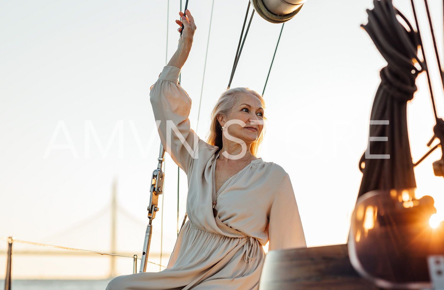 Mature woman on private sailboat looking away at sunset	