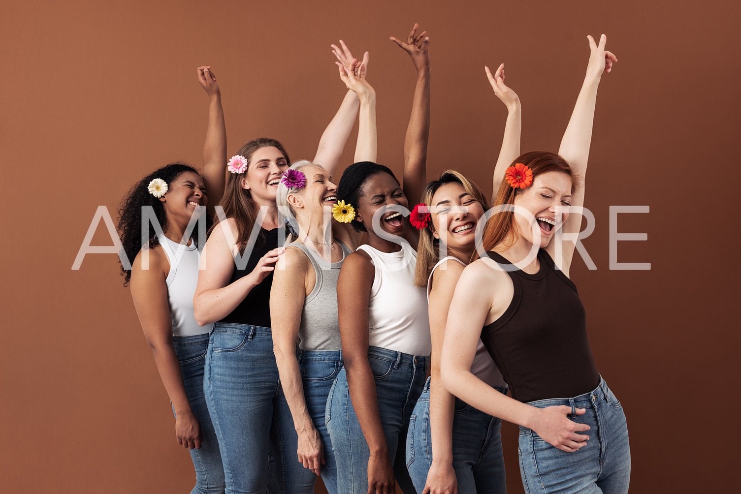 Six laughing women with flowers in hair. Multi-ethnic group of females raises hands up over brown background.