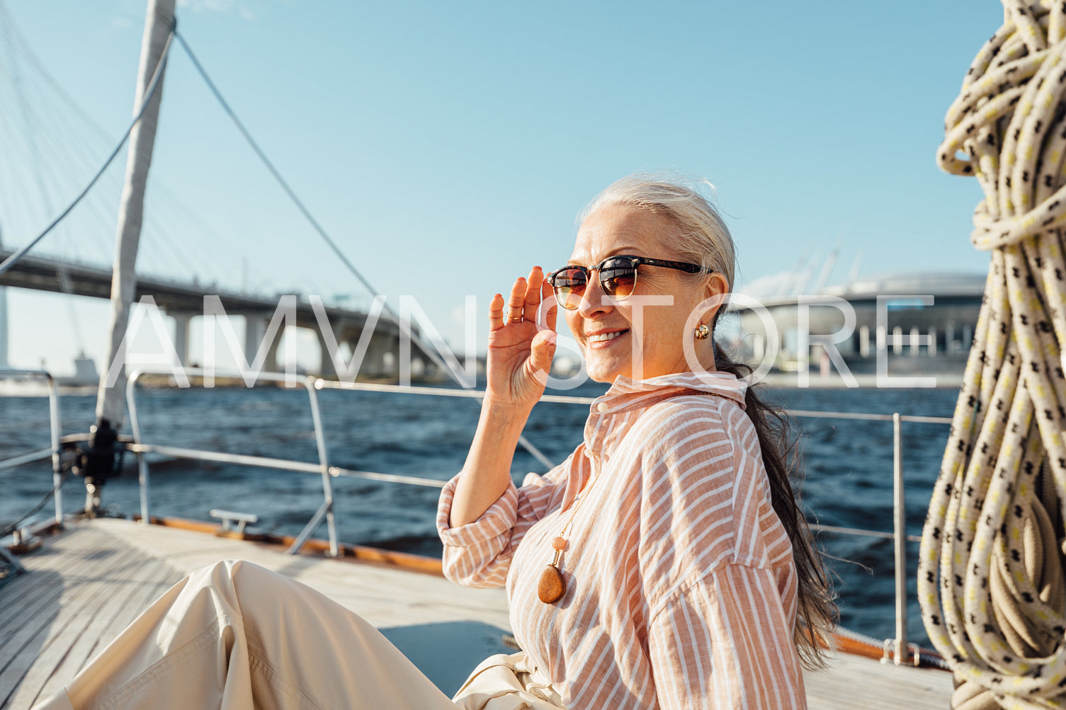 Beautiful senior woman holding a sunglasses and looking away on a private yacht	