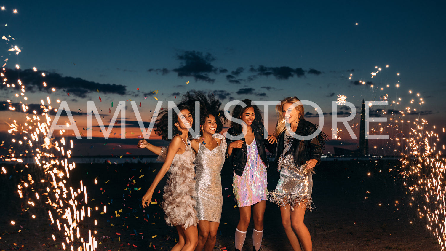 Four women celebrating at sunset. Happy female friends dancing between fireworks at dusk.	