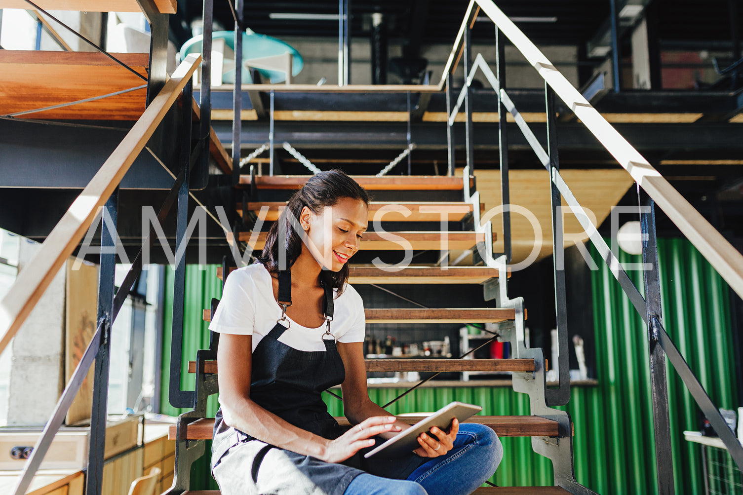 Coffee shop owner sitting on staircase and reviewing business files on digital tablet	