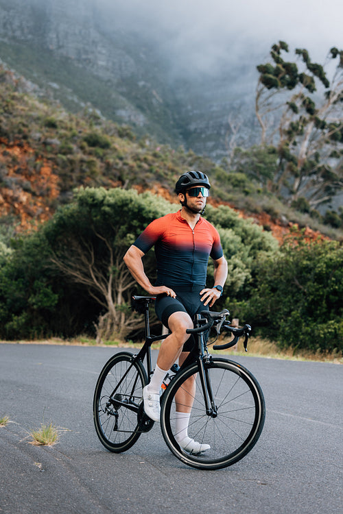 Full length of a professional cyclist. Male road bike rider taking a break.