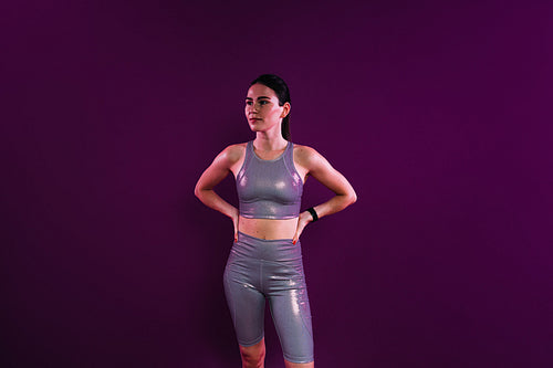 Young sportswoman in silver fitness attire against a magenta background