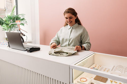 Saleswoman arranging clothes on a counter in store. Clothing sto