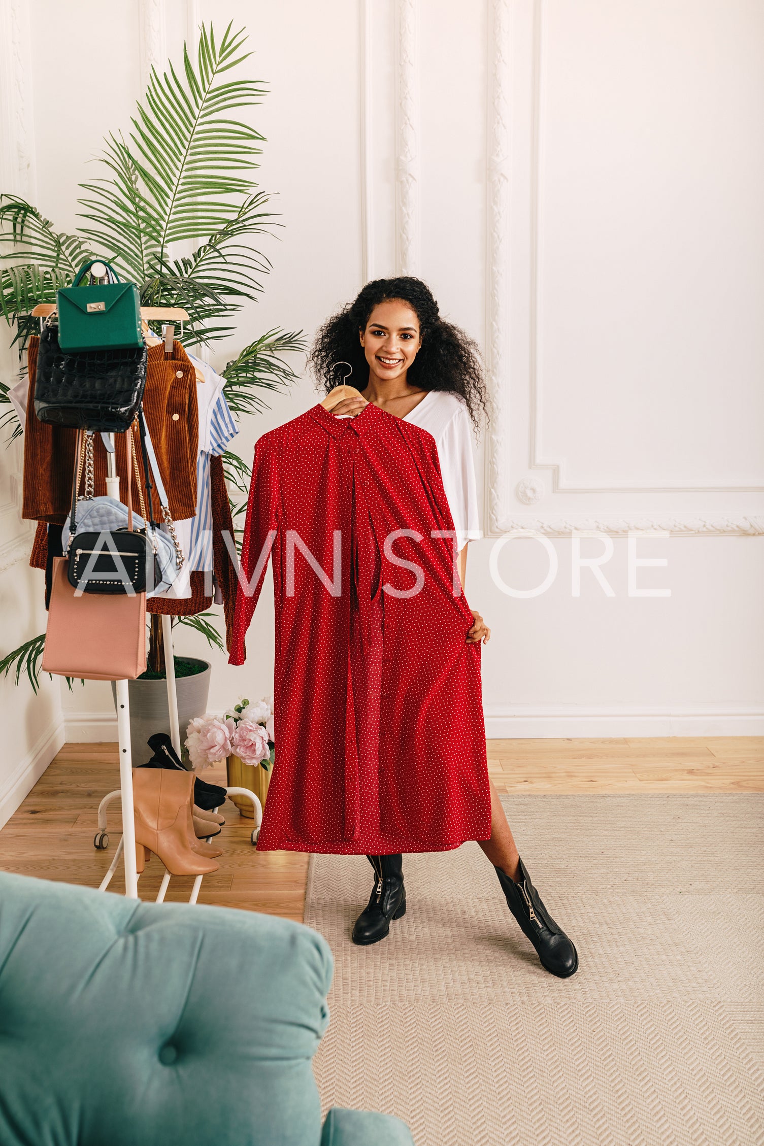 Woman trying on clothes in studio. Fashion stylist standing with red dress.	