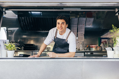 Portrait of a salesman in food truck leaning on counter and looking away