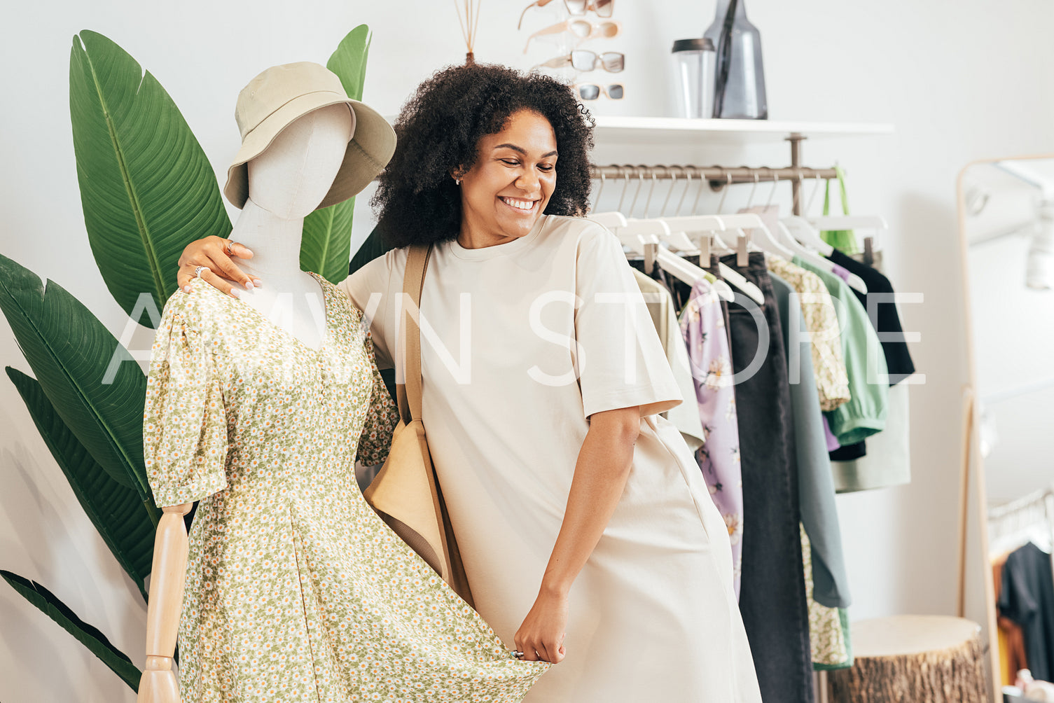 Happy stylish woman embracing mannequin in a small boutique