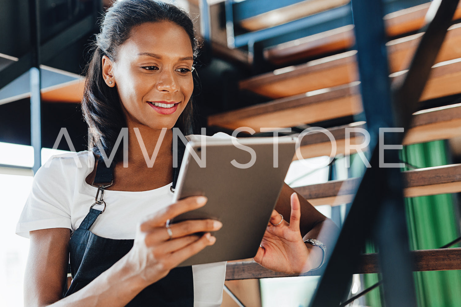 Young coffee shop owner using a digital tablet while sitting on a stairs	