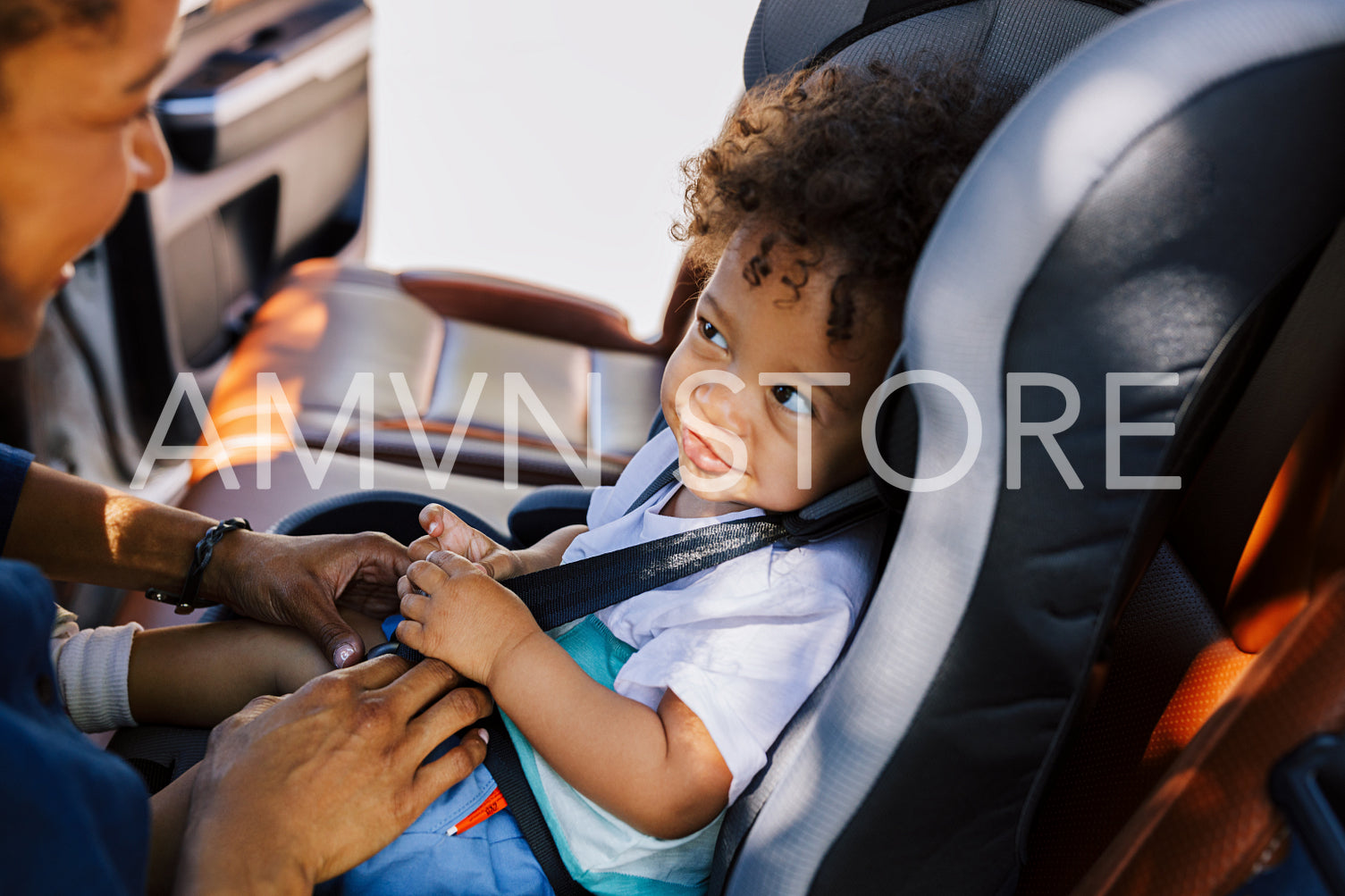 Smiling baby boy looking at his mother while sitting fastened in a car seat	