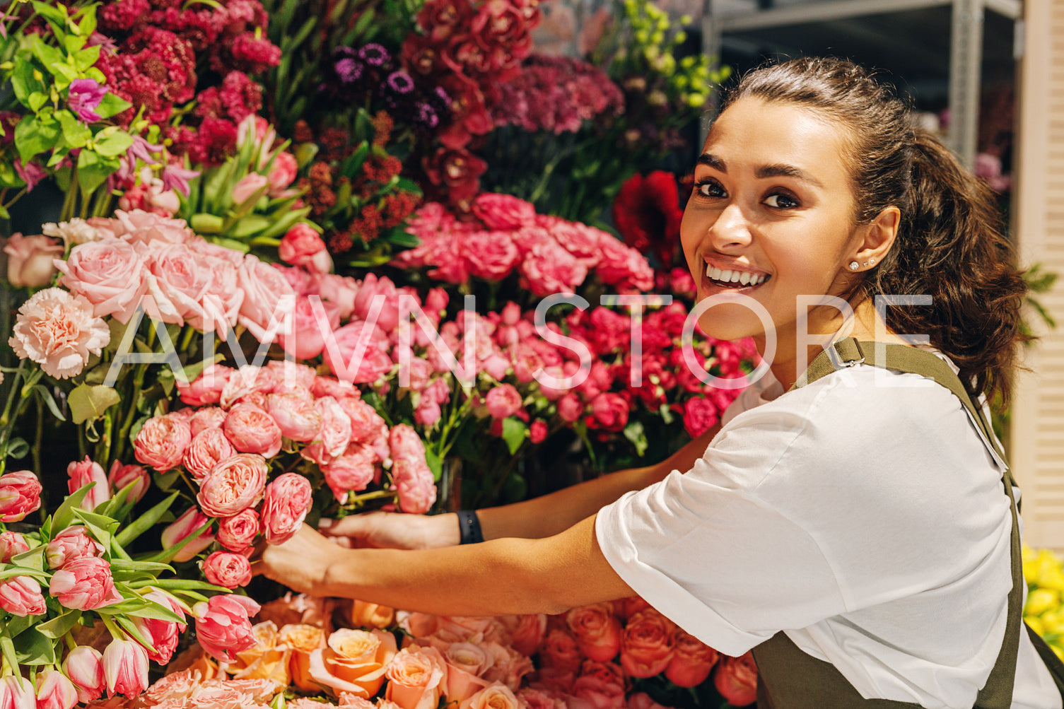 Beautiful florist woman looking at camera in front of a bouquets of flowers	