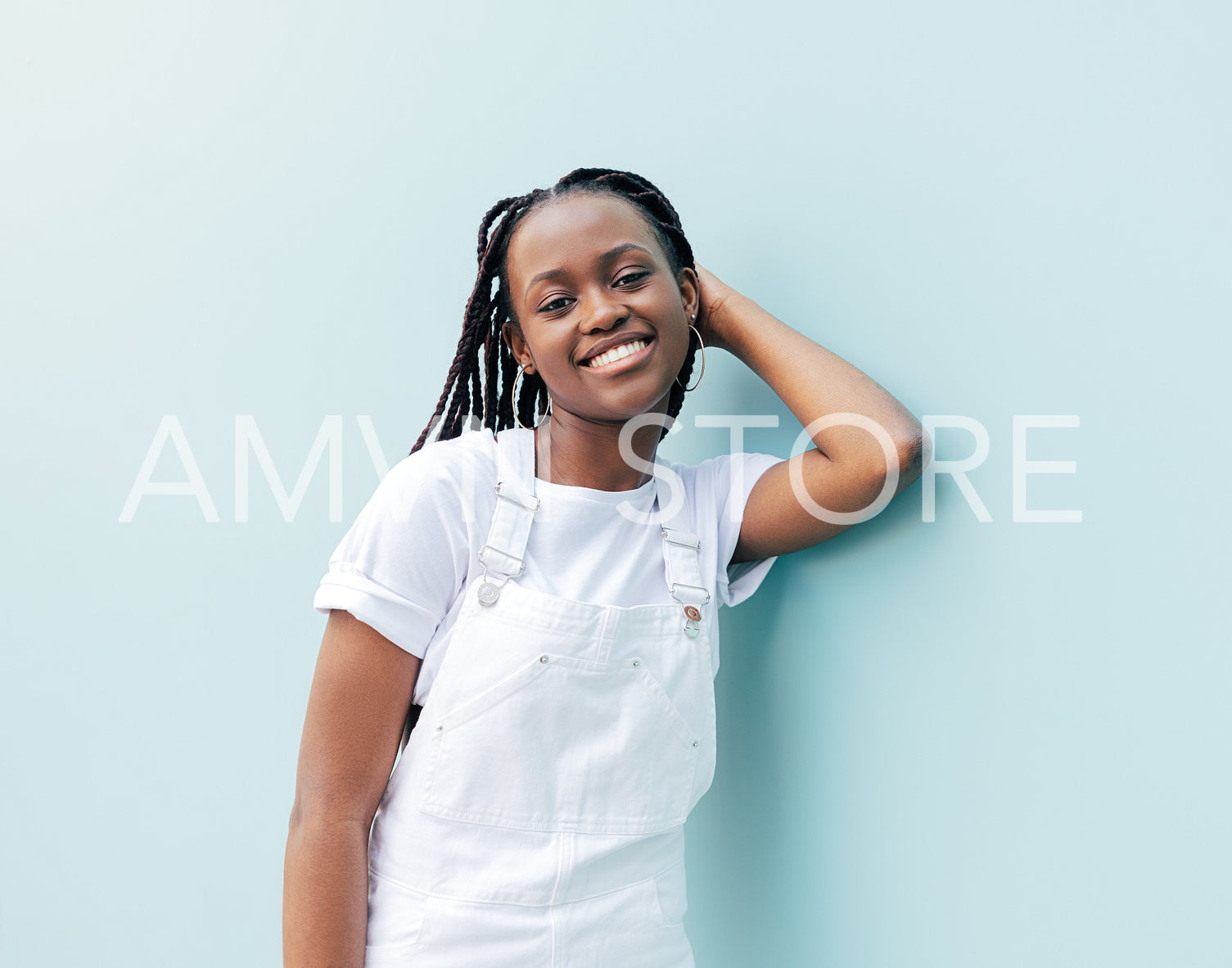 Young smiling girl with braids leaning on the wall and looking at camera